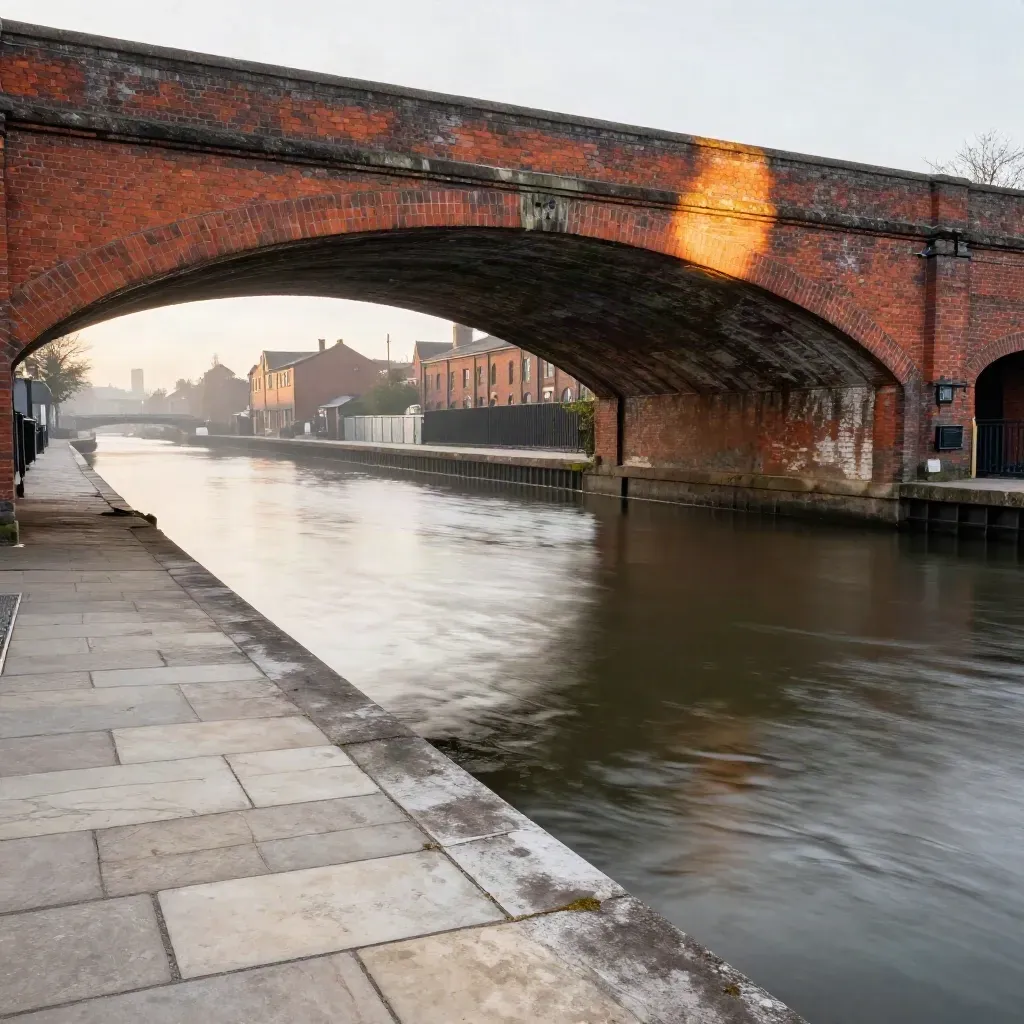 West Midlands canal basin with red-brick arches and calm water in warm late light